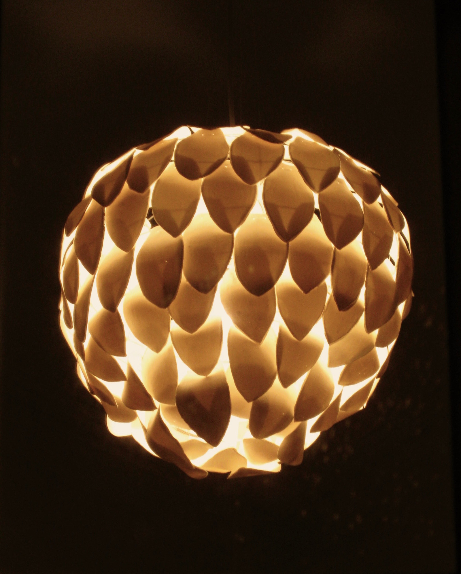 Large chandelier composed of porcelain petals lit in dark room