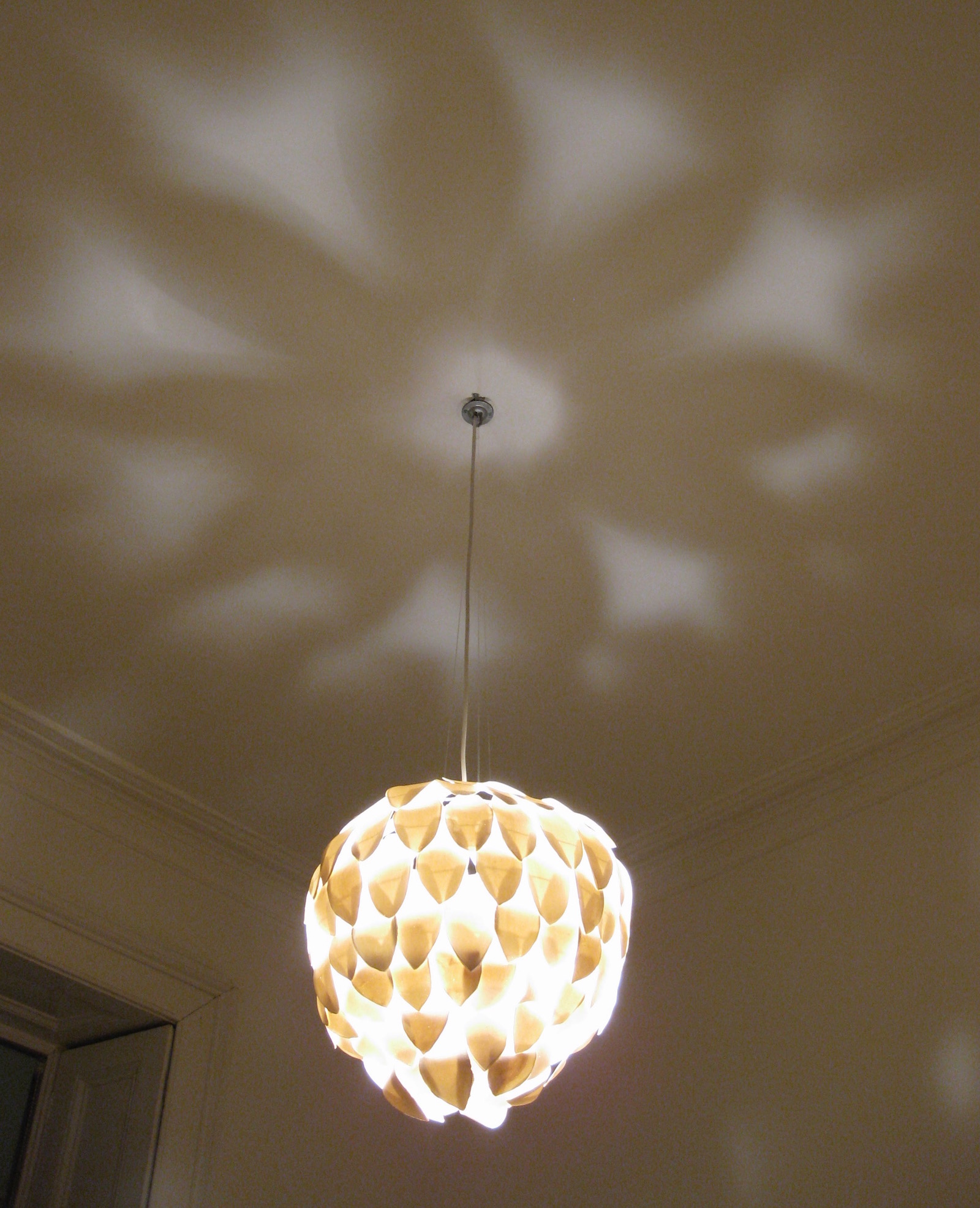 Flower shaped shadows created by chandelier on ceiling