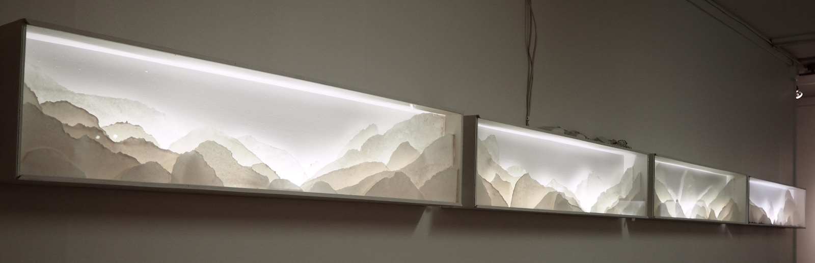 Row of several backlit porcelain landscape dioramas