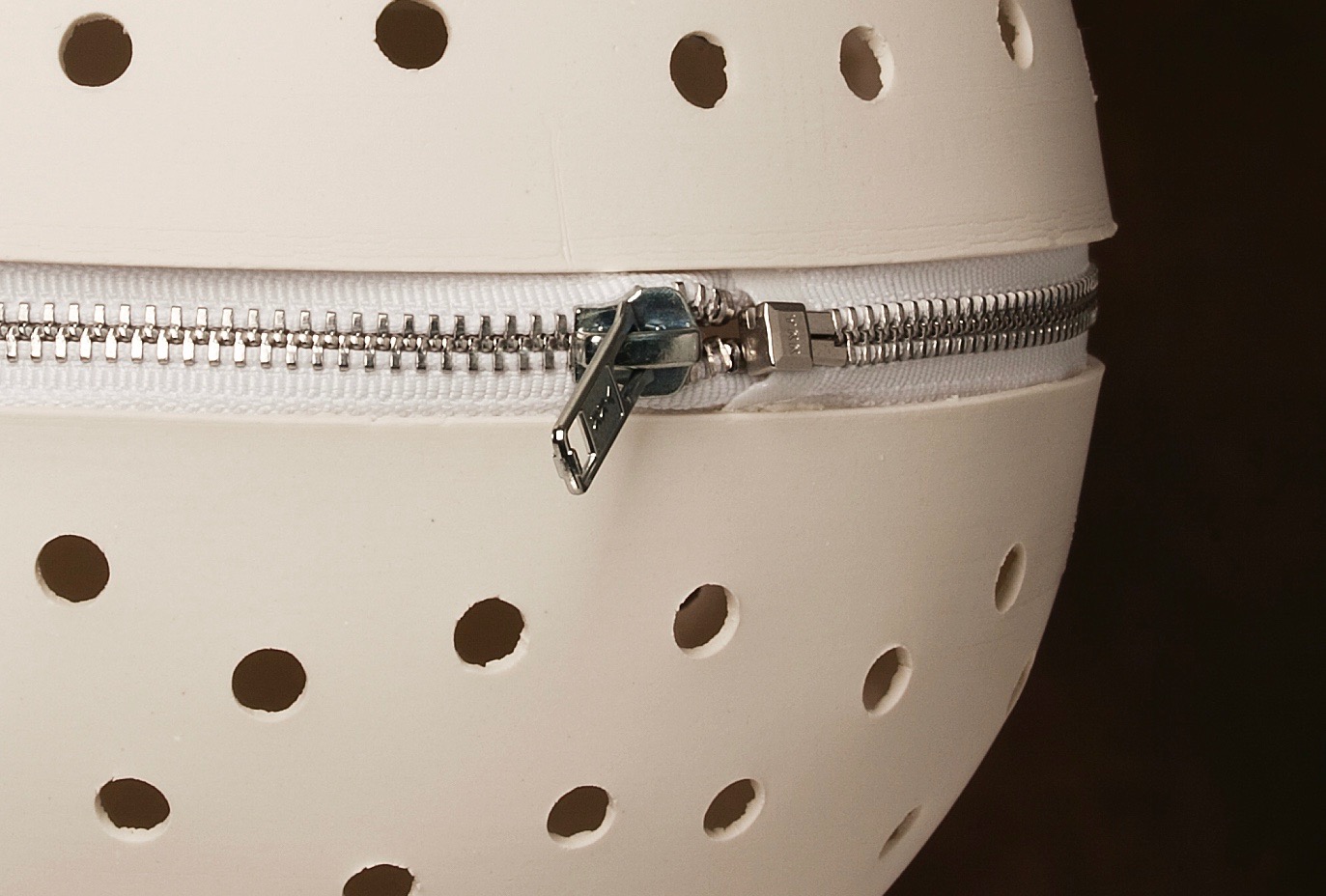 Detail of perforated porcelain globe pendant light with white zip